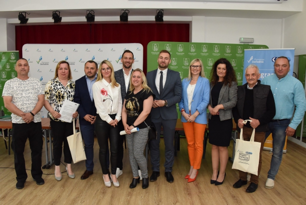 Wspólne zdjęcie Społeczniczek i Społeczników po podpisaniu umów na tle białej i zielonej ścianki 