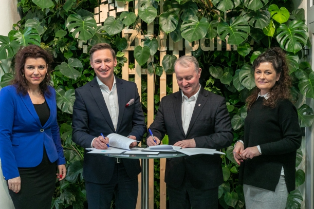 podpisanie umowy w prpgramie społecznik, 4 urzędników - dwie kobiety i dwóch mężczyzn stoją na tle zielonej ścianki  