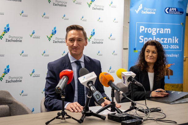 Społeczniczki i Społecznicy z pierwszymi umowami na 2024 rok. Marszałek Geblewicz i prezes KARR Natalia Wegner dziękują społecznikom za złożone wnioski, w tle ścianka promocyjna Pomorza Zachodniego.