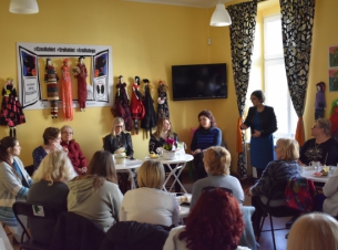 Grupa kobiet siedząca wokół stolików prowadzi rozmowę