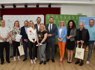 Wspólne zdjęcie Społeczniczek i Społeczników po podpisaniu umów na tle białej i zielonej ścianki 