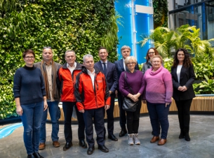 Społecznicy po podpisaniu umów pozuja do wspólnego zdjecia, w tle zieleń w atrium budynku Urzędu Marszałkowskiego przy ulicy Mazowieckiej. 